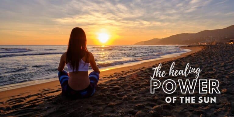 A woman sitting on the beach during sunset sitting indian style sun gazing into the sun