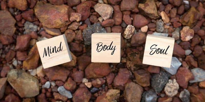 blocks laying on river rocks that say mind body and soul